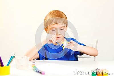 Child painting in art class. Creativity and education concept. Cute little boy paints small figure dinosaur. Children study. Kids Stock Photo