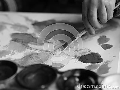 A child paints a picture with a brush and watercolor, blackandwhite picture Stock Photo