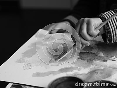 A child paints a picture with a brush and watercolor, blackandwhite picture Stock Photo