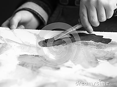 A child paints a picture with a brush and watercolor, blackandwhite picture Stock Photo