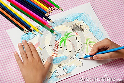 Child paints a picture of pencils pirate treasure map. Stock Photo