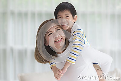 Child on a piggy back ride with his mother at home Stock Photo