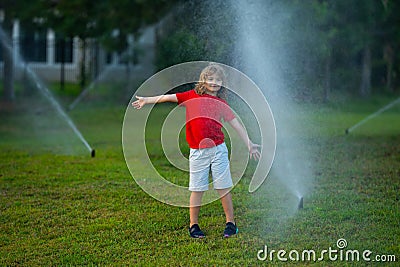 Child play near automatic sprayers in the garden. Watering in the garden. Kid freshness of nature. Automatic lawn Stock Photo