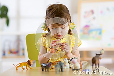 Child playing with animal toys at table in kindergarten or home Stock Photo