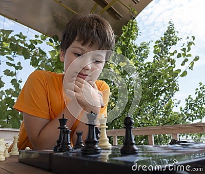 Child playing chess outdors, Young boy making a move Stock Photo