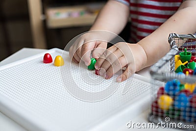 Child playing with colorful toys sitting at a window. Little boy Stock Photo