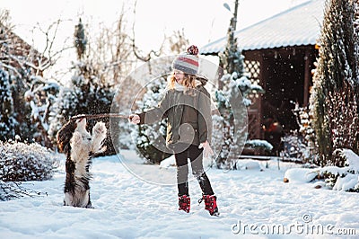 Child playing with dog outdoor in snowy winter garden Stock Photo