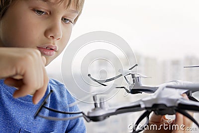 Child playing with drone. Boy near the window holding quadrocopter in his hand. Technology, leisure toys concept Stock Photo