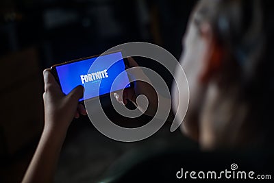Child playing Fortnite on a mobile phone Editorial Stock Photo