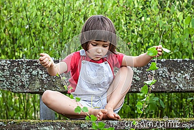 Child playing with ivy stems to learn nature in garden Stock Photo