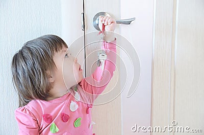 Child playing with keys forgotten by parents in door keyhole. Children safety and home safety Stock Photo