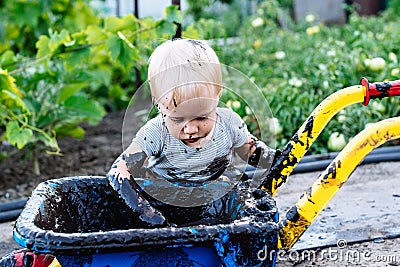 Child playing in the mud on the street Stock Photo