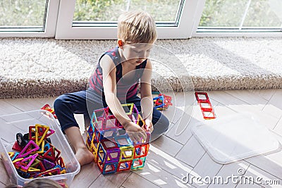 The child is playing with a multi-colored magnetic constructor, building a tower. Educational toys . A building block for a baby Stock Photo