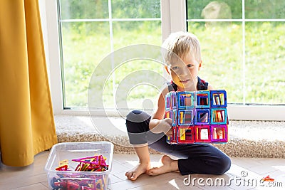The child is playing with a multi-colored magnetic constructor, building a tower. Educational toys . A building block for a baby Stock Photo