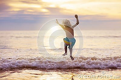 Child playing on ocean beach. Kid at sunset sea Stock Photo