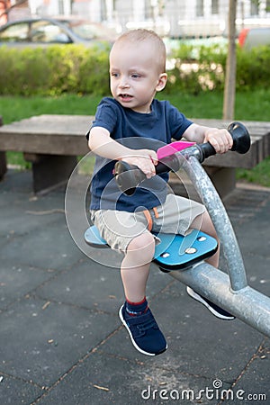 Child playing on outdoor playground in summer. Kids play on kindergarten yard. Active kid on colorful swing. Healthy Stock Photo