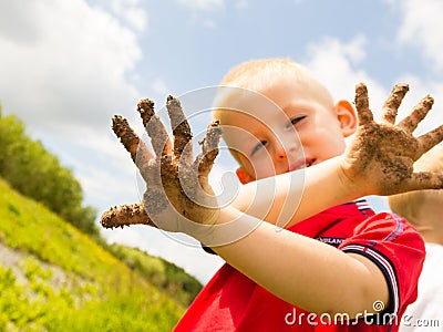 Child playing outdoor showing dirty muddy hands. Stock Photo