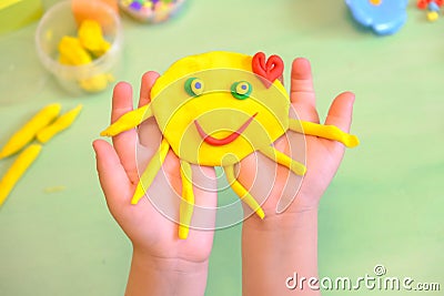 Child playing with plasticine, colorful modeling clay and sculpting funny sun . Home Education game with clay. Early development Stock Photo