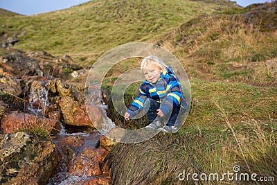 Child playing on a pond in geothermal area in Krysuvik on early sunny morning, Southern Peninsula Reykjanesskagi, Reykjanes Stock Photo