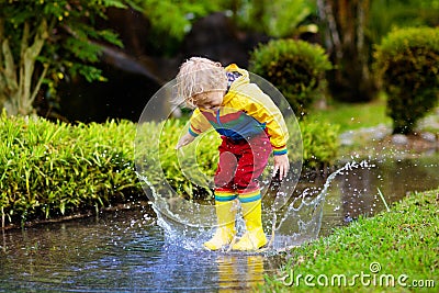 Child playing in puddle. Kids jump in autumn rain Stock Photo