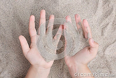 The child is playing with the sea sand. Sypet, flying away. Relax, meditation Stock Photo