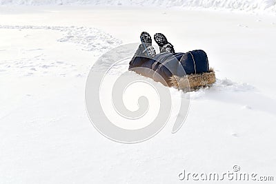 The child is playing in the snow. Lying buried. On the feet, the shoes support the straps pins from the winter jumpsuit Stock Photo