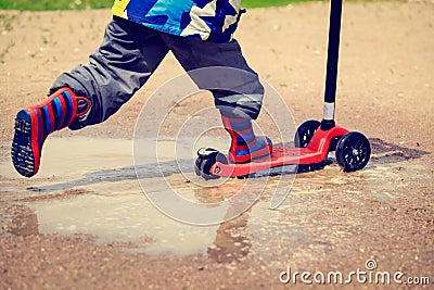 Child playing in water puddle, kids outdoors Stock Photo