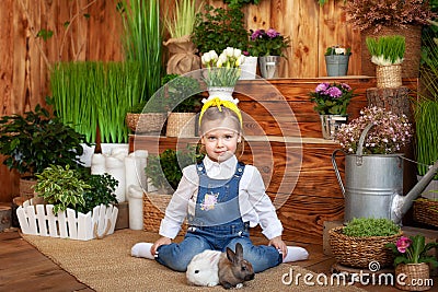 Child playing with white rabbits. Little girl feeding and petting white bunnys. Easter celebration. Egg hunt with kid and pet anim Stock Photo