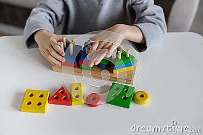 A child plays with a colored educational wooden toy at home.Close-up Stock Photo