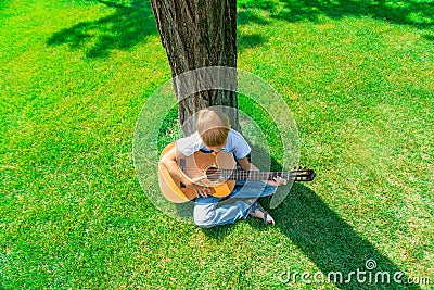 The child plays the guitar in nature, top view Stock Photo