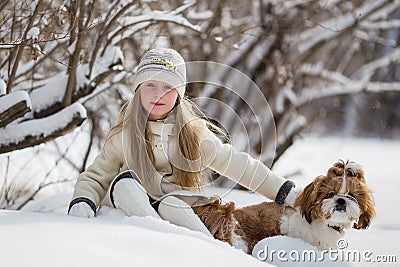 Child plays with his pet on Christmas holidays in forest. Beautiful girl smiles, caresses her beloved dog in winter in park Stock Photo