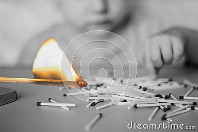 A child plays with matches in the foreground a burning match, a child and matches, a fire, dangerous, black and white Stock Photo