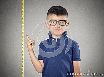 Child pointing at his height on measuring tape Stock Photo