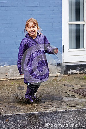 Child, portrait and splash in mud puddle in raincoat for winter fun, explore city or cold weather happy. Young girl Stock Photo