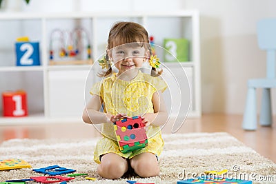 Child preschooler girl plays logical toy learning shapes and colors at home or nursery Stock Photo