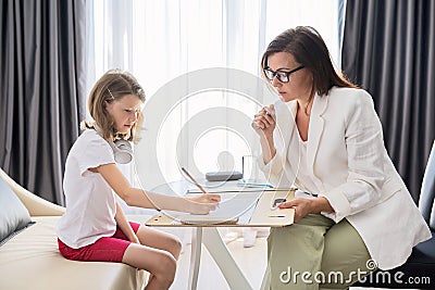 Child psychologist talking to girl kid in office Stock Photo