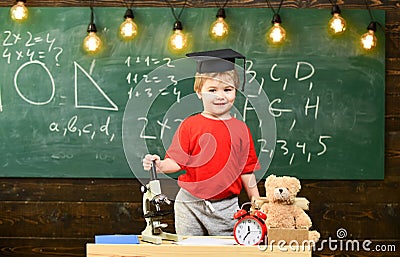 Child, pupil on smiling face near microscope. First former interested in studying, education. Wunderkind concept. Kid Stock Photo