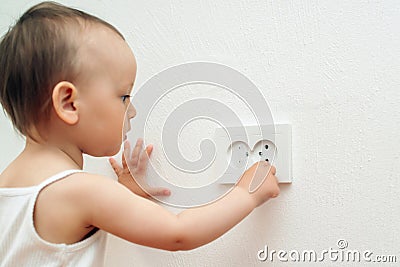 Child put finger in socket. Baby touching the power socket Stock Photo