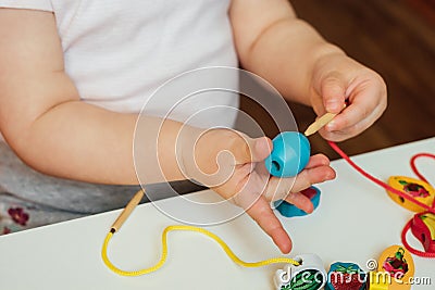 Child putting beads on a string. Bead stringing activity. Fine motor skills development Stock Photo