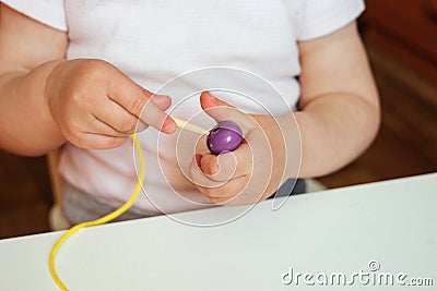 Child putting beads on a string. Bead stringing activity. Fine motor skills development Stock Photo