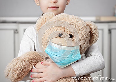 Child on quarantine due epidemic of coronavirus COVID-19. Child girl cuddle toy bear wear medical mask Stock Photo