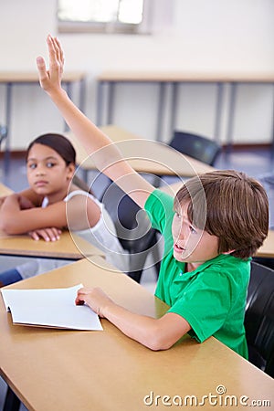 Child raise his hand in school for questions, support and help with classroom education and teaching in school Stock Photo