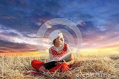 Child reading book or bible outdoors . Young Child`s Hands Praying on Holy Bible . Stock Photo