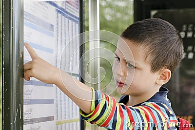 Child reading timetable at bus stop Stock Photo