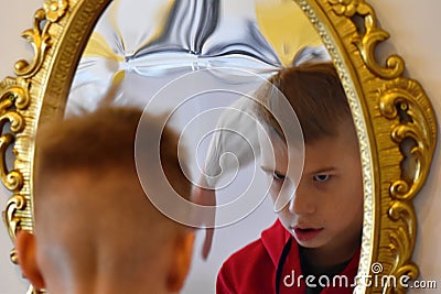 The child reflected in a distorting mirror. A fun reflection of the boy. Children`s entertainment Stock Photo