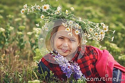 A child rests in a field with a wreath of field daisies Stock Photo