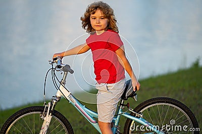 Child riding bicycle. Little kid boy on bicycle along bikeway. Happy cute little boy riding bicycle in summer park Stock Photo