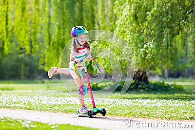 Child riding kick scooter in summer park. Stock Photo