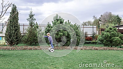 Child riding on self-balancing hover board on the backyard of cottage, outdoor kids activity Stock Photo