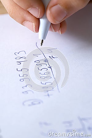 child, right-handed schoolchild hesitantly solves difficult task of adding numbers, 5th grade student writes down numbers in Stock Photo